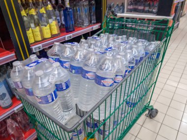 Fransa, 12 Ağustos 2024: Bir süpermarket koridorunda şişe suyla dolu alışveriş arabası