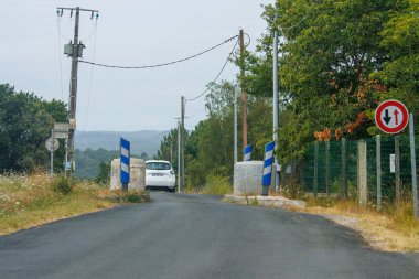 Fransa, 15 Ağustos 2024: Dar bir köprü ve trafik işaretine yaklaşan bir arabalı köy yolu