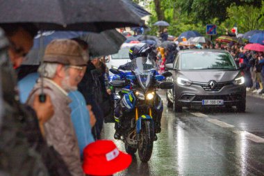 Fransa, 22 Mayıs 2024: Şemsiye altındaki kalabalık yağmurda araç ve motosiklet geçit törenini izliyor