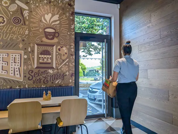 Fransa, 9 Eylül 2024: Müşteri paket paketiyle bir fast food restoranından ayrılıyor