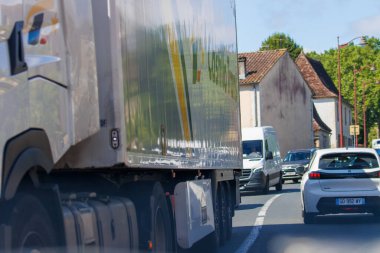Fransa, 1 Temmuz 2024: Konut alanından geçen kamyon ve araçlarla dolu yoğun bir yolda trafik