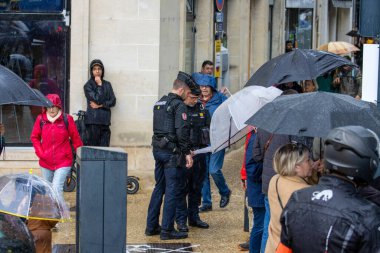 Fransa, 22 Mayıs 2024: Şemsiyeli insanlar açık hava olayları sırasında polis memurlarının yanında yağmurda toplandı