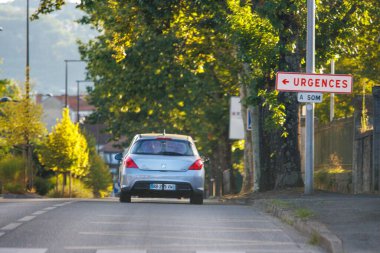 Fransa, 10 Ağustos 2024: Bir banliyö caddesinde araba sürmek ve ileride acil servisleri işaret eden bir tabela