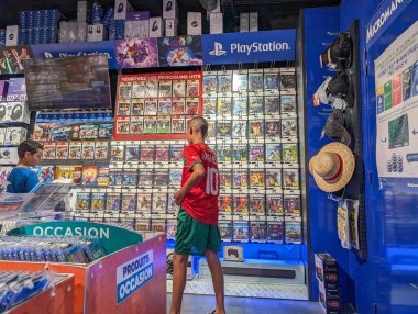 Fransa, 19 Ağustos 2024: PlayStation ekranı ve ön ürünler bölümü olan bir mağazada müşterilerin video oyunlarına göz atması