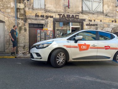 Fransa, 22 Temmuz 2024: CBS servis aracı tarihi bir kasabadaki eski bir Tabac mağazasının önüne park edildi
