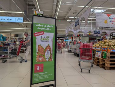 Fransa, 19 Ağustos 2024: Süpermarket koridoru müşteriler ve saçma reklam panosuyla dolu