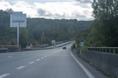 Fransa, 08 Eylül 2024: Bulutlu gökyüzünün altındaki yemyeşil orman manzarası boyunca bomboş otoyol