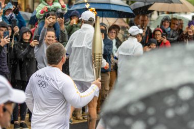 Fransa, 22 Mayıs 2024: Paris 2024 Olimpiyat meşalesi yağmurlu hava altında seyircilerle