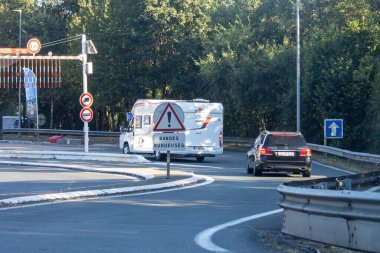 Fransa, 10 Ağustos 2024: Uyarı işareti ve ağaçların altındaki yol bariyeri yakınındaki araçlar