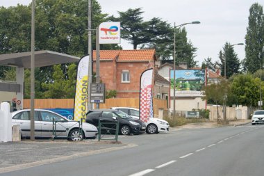 Fransa, 15 Ağustos 2024: Benzin istasyonu, kullanılmış araba galerisi, konut alanı, yol, reklam tabelaları