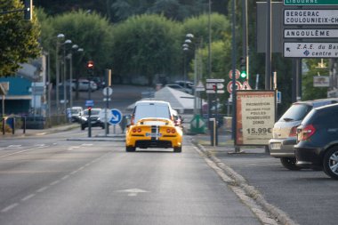 Fransa, 10 Ağustos 2024: Sarı spor araba şehir caddesinde yön işaretleriyle ilerliyor