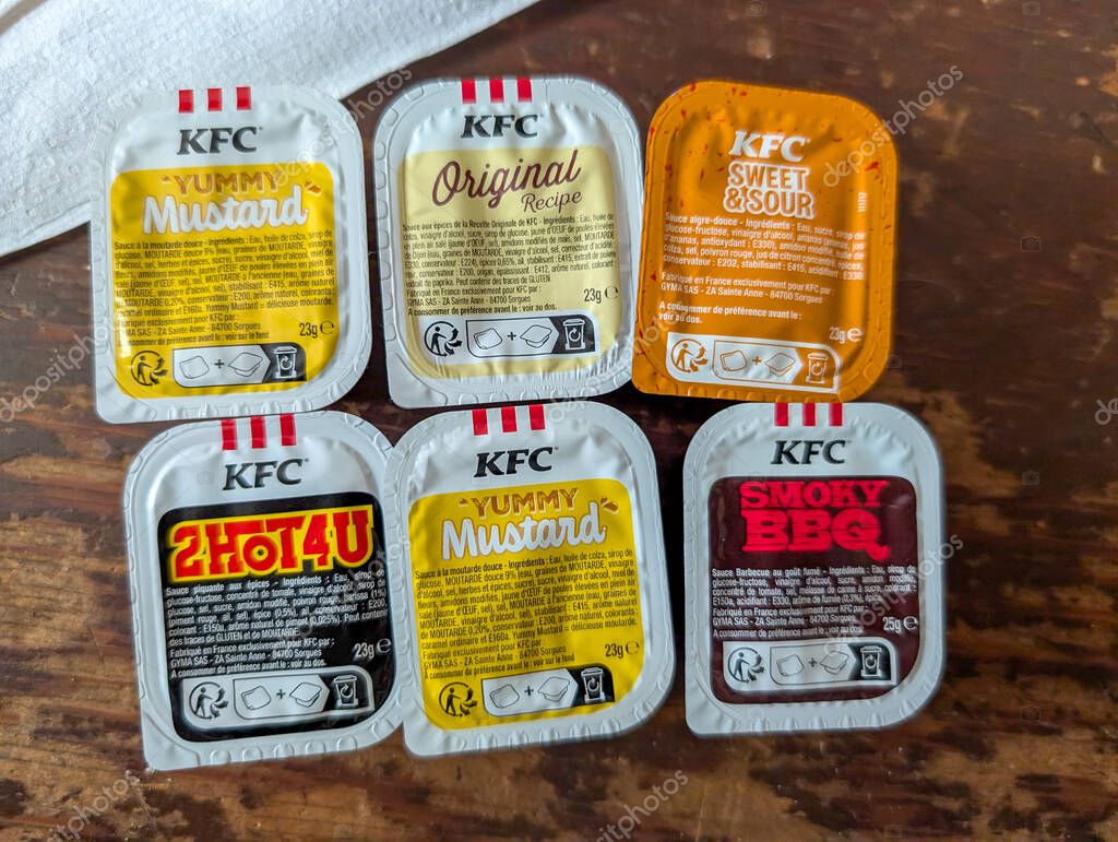 France, 18 August 2024 : Assorted KFC sauce packets on a wooden table surface