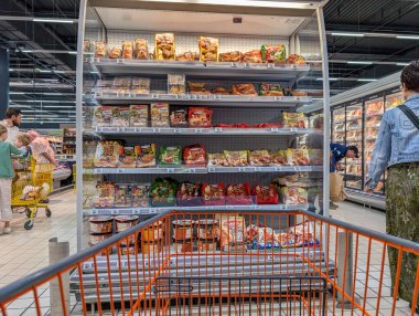 Fransa, 26 Ağustos 2024: Arka planda paketlenmiş gıda ürünleri ve müşterilerin raflarıyla market koridoru