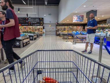 France, 27 August 2024: Interior of supermarket with shopping cart and people browsing aisles clipart