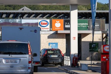 Fransa, 10 Ağustos 2024: Esso ve Franprix logoları yakınlarındaki benzin istasyonunda arabalar