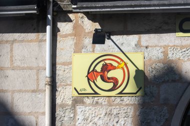 Fransa, 16 Ağustos 2024: Taş bir binanın üzerinde kırmızı ejderha logosu bulunan duvara monte edilmiş tabela
