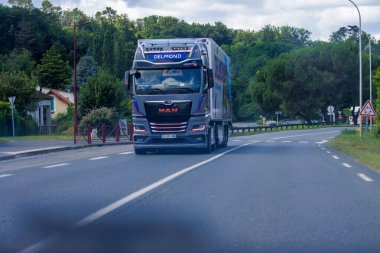 France, 1 July 2024: Large MAN truck driving on a rural road near greenery clipart