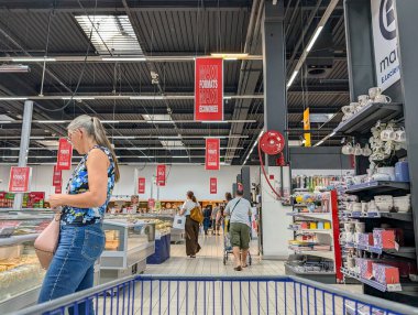 France, 27 August 2024 : Woman Shopping in Grocery Store with Blue Floral Top clipart