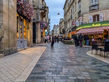 Fransa, Bordeaux, 05 Ekim 2024: Cobblestone Caddesi 'nde açık kafe ve dükkanlardan keyif alan insanlar.