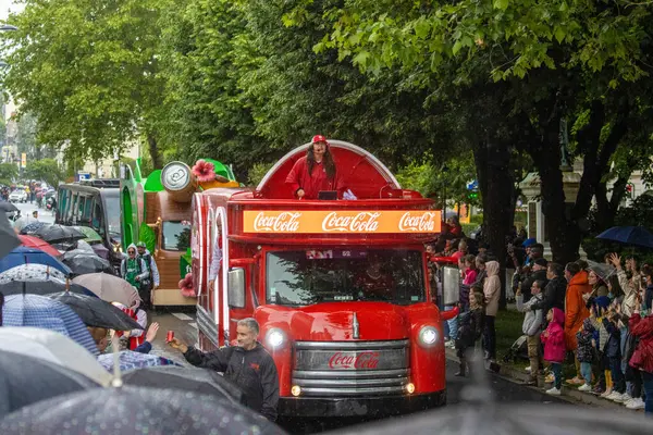 Fransa, 21 Ağustos 2024: Coca-Cola kamyonu yağmurlu bir günde kalabalığın gözü önünde geçit törenine katılıyor