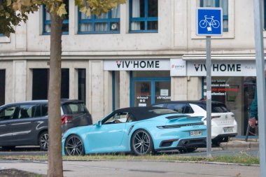 France, 08 September 2024 : Blue sports car parked near VIV'HOME building entrance. clipart