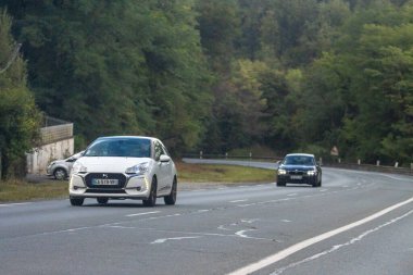 Fransa, 08 Eylül 2024: Dönen orman yolunda beyaz araba ve siyah araba