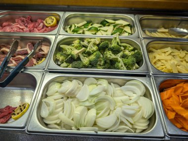 Fransa, 3 Ağustos 2024: Soğan, brokoli, havuç ve et de dahil olmak üzere çeşitli taze sebzelerle açık büfe