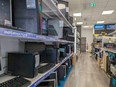 Fransa, 24 Ağustos 2024: Bir teknoloji mağazası koridorunda sıralanmış bilgisayar ve aksesuarlar