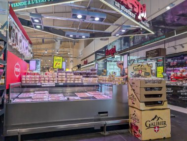 France, 15 August 2024: Interior of a butcher shop at a market displaying meats and Galibier beer crates clipart