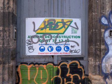 Fransa, Bordeaux, 05 Ekim 2024: İnşaat tabelasına güvenlik ekipmanları simgeleriyle grafiti