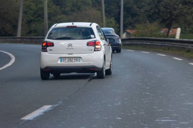 Fransa, 08 Eylül 2024: Beyaz Citroen arabası dolambaçlı bir orman yolunda ilerliyor