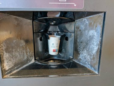 Fransa, 08 Eylül 2024: Kahve makinesi görünür aşınma ve kir dolu bardak dağıtıyor