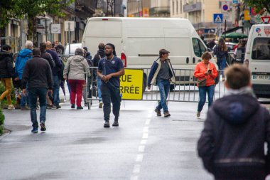 Fransa, 22 Mayıs 2024: Sokakta yol levhası ve arka planda minibüsle yürüyen insanlar