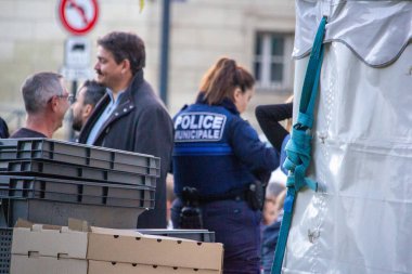 Fransa, 28 Eylül 2024: Belediye polisi pazar tezgahı yakınlarındaki insanlarla etkileşim halinde.