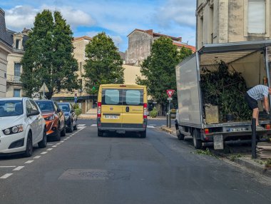 Fransa, 13 Ağustos 2024: İşçi kamyonu park halindeki araçlarla dolu bir iskan caddesine boşaltıyor