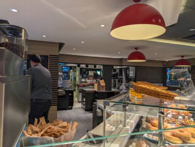 Fransa, 21 Eylül 2024: Kırmızı ışıklar altında hamur işleri ve kahve makineleriyle dolu kafe.