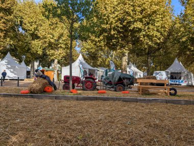 France, 27 September 2024 : Autumn festival scene with hay bales, pumpkins, and tents.