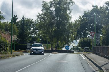 Fransa, 08 Eylül 2024: Arabalar güneşli banliyö yolunda yol ayrımına yaklaşıyor