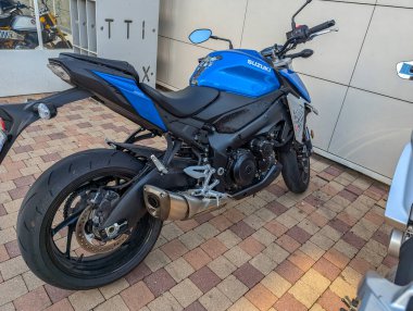 Fransa, 20 Ağustos 2024: Mavi Suzuki motosikleti tuğla desenli kaldırıma park edildi