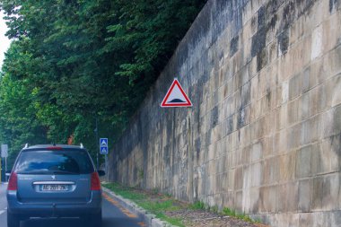 Fransa, 01 Temmuz 2024: Ağaçlı duvar yolu boyunca trafik işaretlerinin yanında araba sürmek