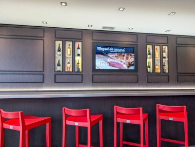 Fransa, 18 Ekim 2024: Duvarında kırmızı sandalyeler ve şarap sergisi olan bar.