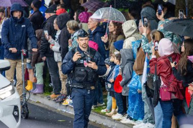 Fransa, 22 Mayıs 2024: Şemsiye altında polis memuru ve izleyicilerle dolu kalabalık cadde