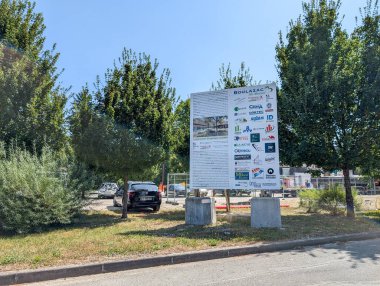 Fransa, 31 Temmuz 2024: Ağaçlarla çevrili inşaat projesinin ayrıntılarını gösteren büyük ilan panosu