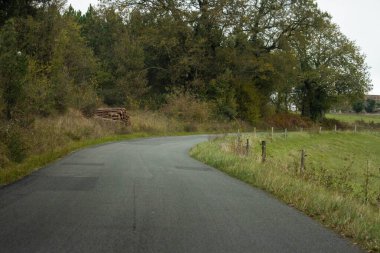 Dordogne Fransa 'da ağaçlar ve kütükler ile kırsal yol kıvrımlı