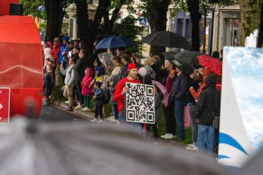 France, 22 May 2024: Crowd standing in rain during public event, person holding QR code sign clipart