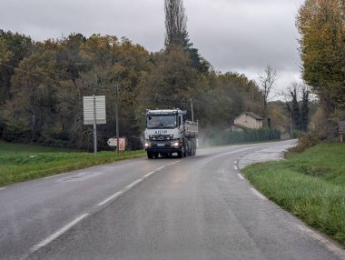 Dordogne Fransa kırsalında yağmurlu bir yolda giden bir kamyon.