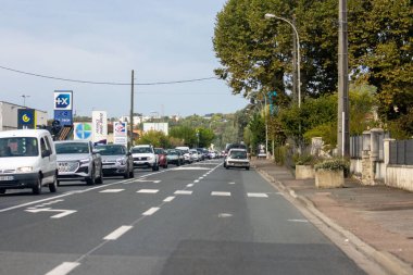 Fransa, 21 Eylül 2024: Ağaçlar ve çeşitli işletmelerle dolu yoğun anayol.
