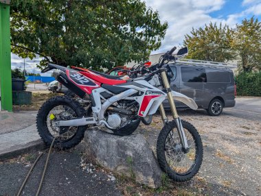 Fransa, 13 Ağustos 2024: off-road motosikleti arka planda bir kamyonetle dışarıda bir kayanın üzerinde park edilmiş.