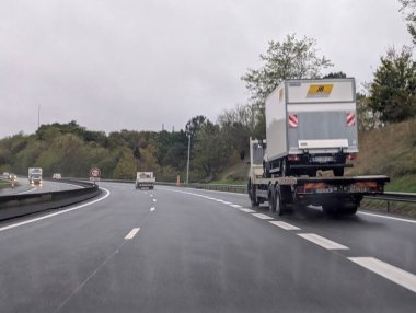 Fransa, 19 Kasım 2024: Kamyon bulutlu bir karayolunda büyük bir konteynır taşıyor.