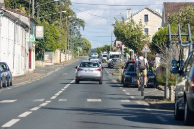 Fransa, 08 Eylül 2024: Banliyö bölgesinde otomobil ve evlerle birlikte yoldaki bisikletçi